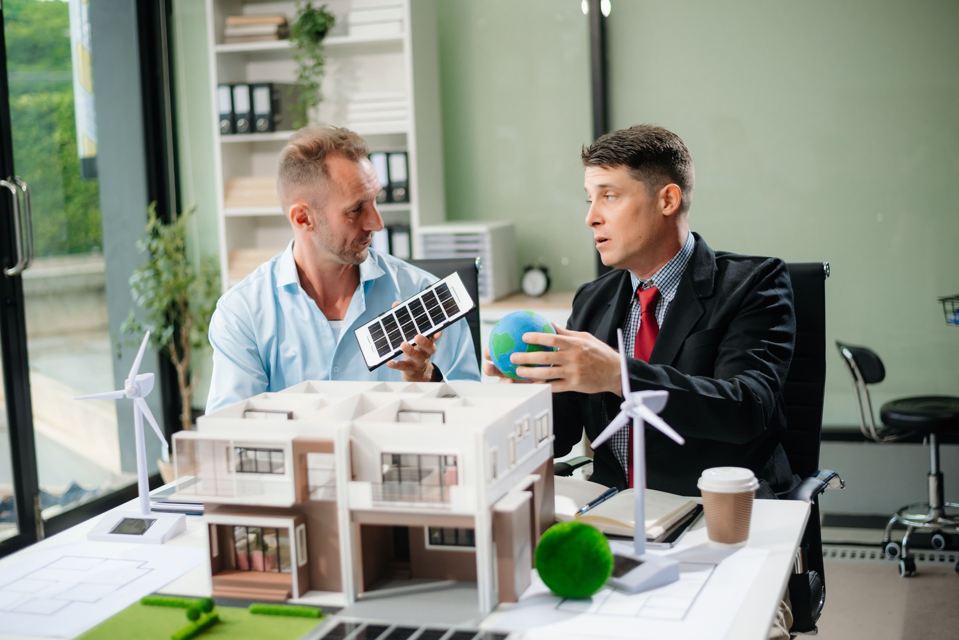 Experts collaborate on renewable energy solutions with house models, wind turbines, and solar panels, emphasizing green design